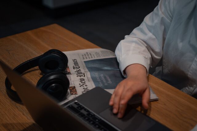 Ziar economic deschis la pagina cu grafice, lângă o ceașcă de cafea, pe o masă de lemn