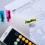 Teanc de facturi și un laptop pe biroul unei firme mici, pregătite pentru verificarea încasărilor