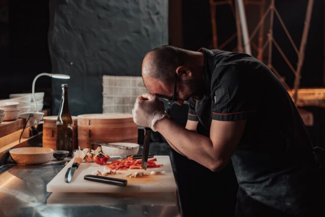 Masă de restaurant aranjată pentru cină, cu pahare și tacâmuri, dar cu scaunele goale, într-o seară aglomerată