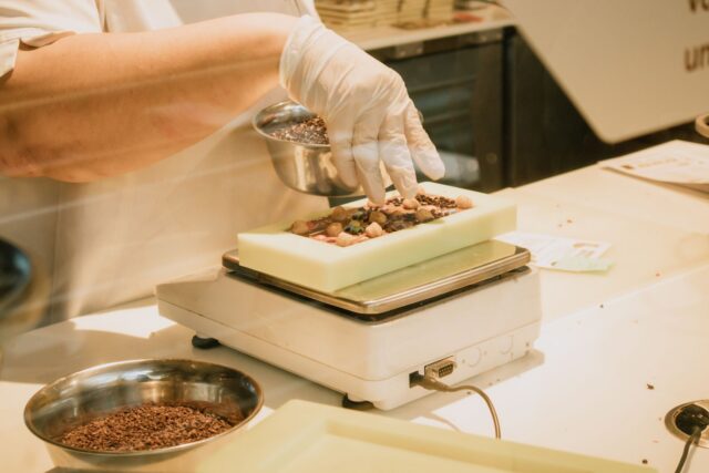 Bucătar care cântărește ingrediente pe un cântar digital într-o bucătărie profesională de restaurant