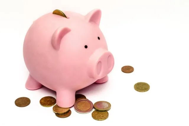 Pușculiță și monede așezate lângă un calendar, simbol al economiilor