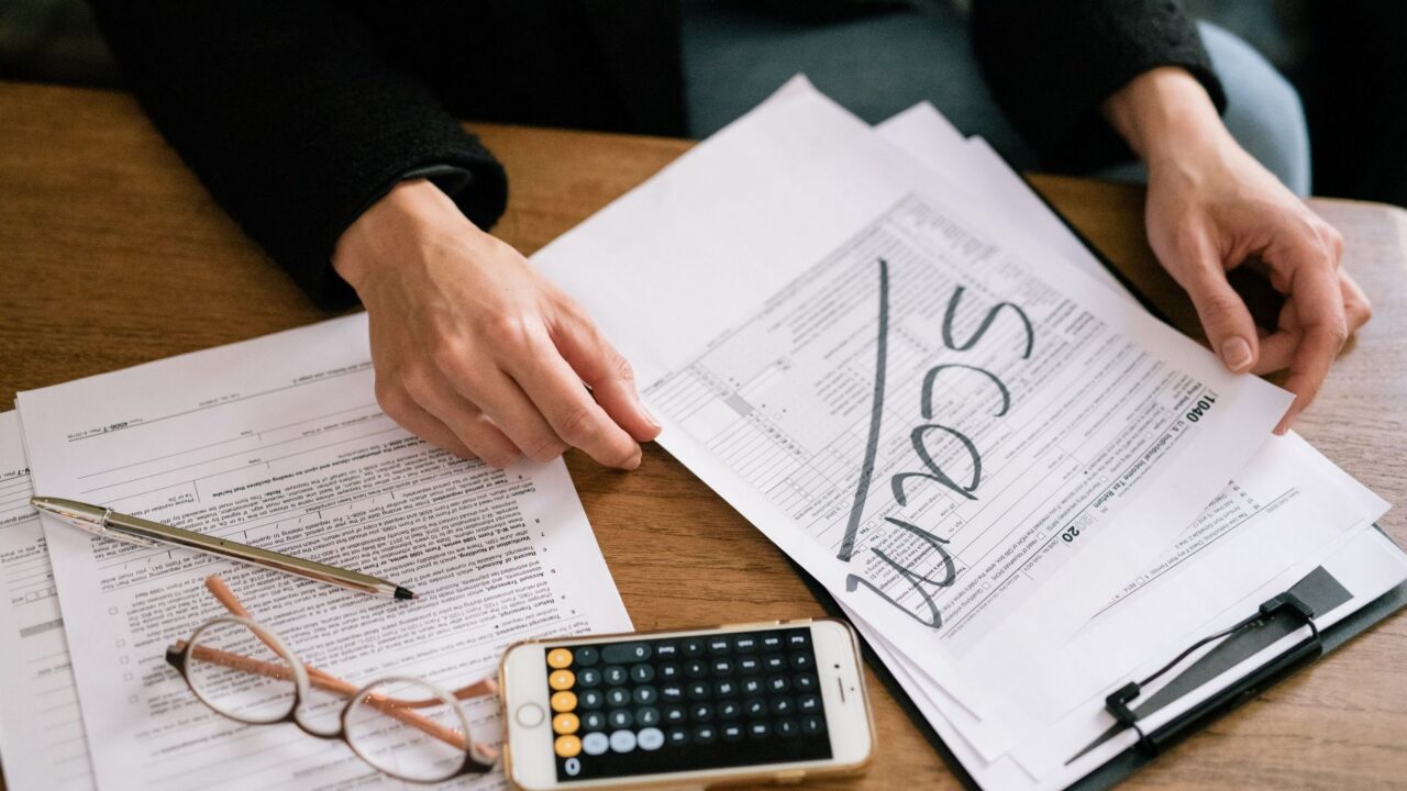 Formulare fiscale, un calculator și un pix pe o masă de lucru, pregătite pentru completarea declarațiilor