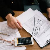Formulare fiscale, un calculator și un pix pe o masă de lucru, pregătite pentru completarea declarațiilor