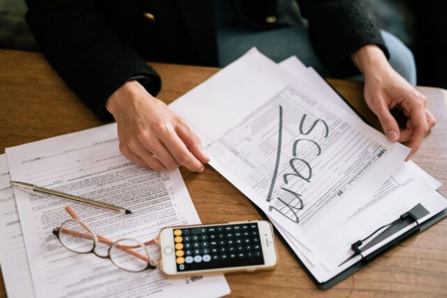 Formulare fiscale, un calculator și un pix pe o masă de lucru, pregătite pentru completarea declarațiilor